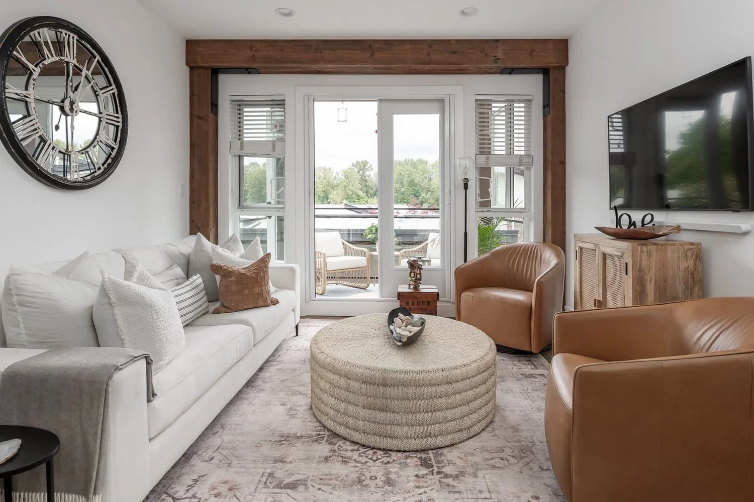 Living room with white linen sofa, leather club chairs, and reclaimed timber door frame
